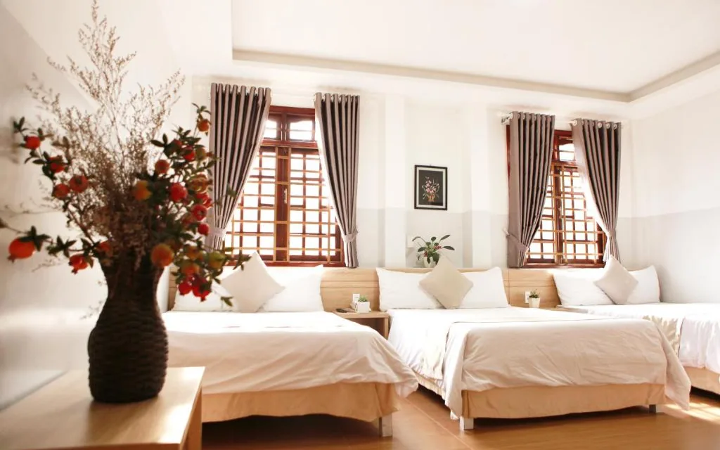 Phòng Suite Family khách sạn Ngọc Nguyên Anh Đà Lạt: các giường xếp cạnh nhau, cửa sổ gỗ