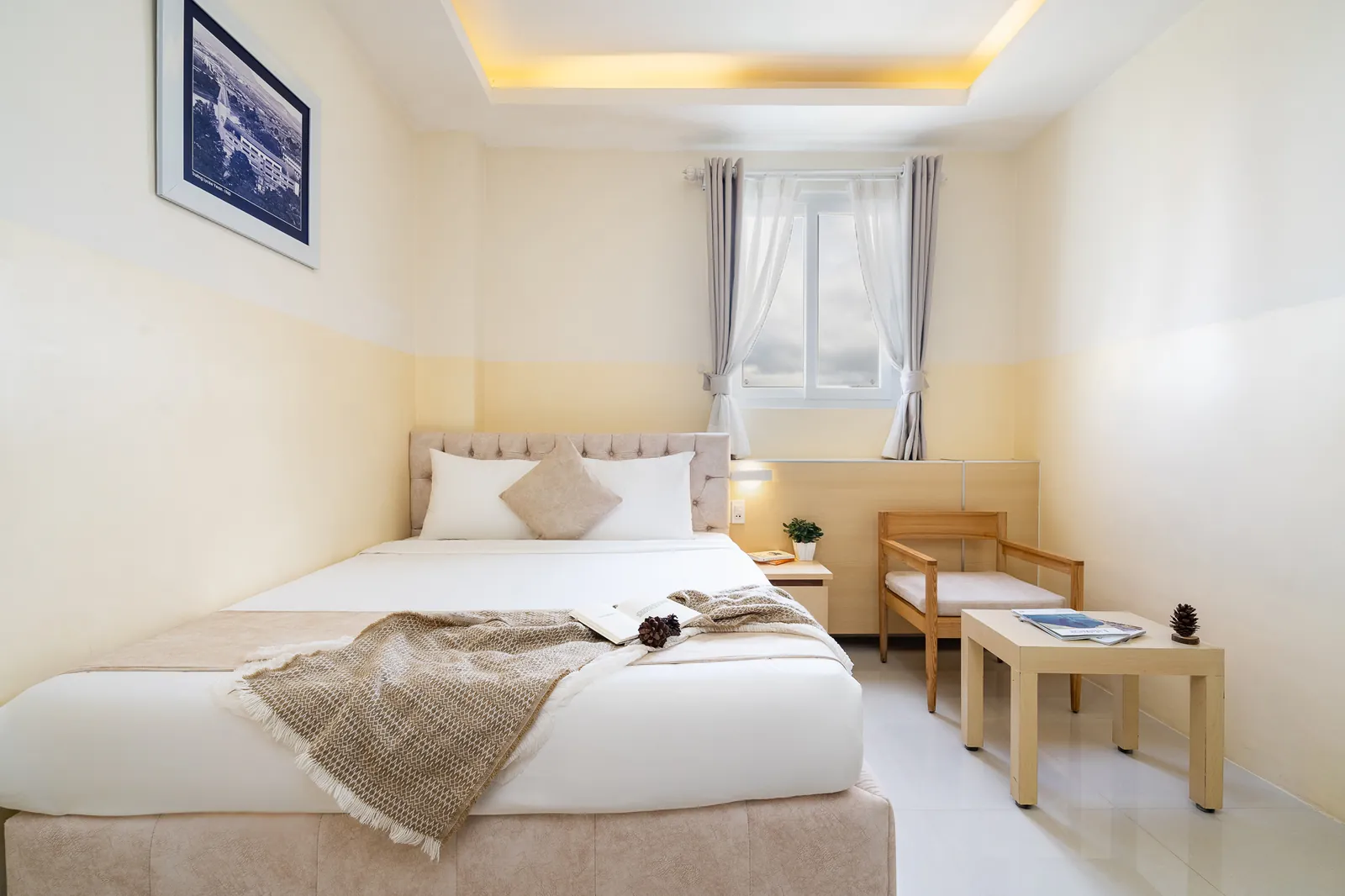 Giường 1.6m, ghế gỗ và bàn nhỏ cạnh cửa sổ trong phòng Deluxe