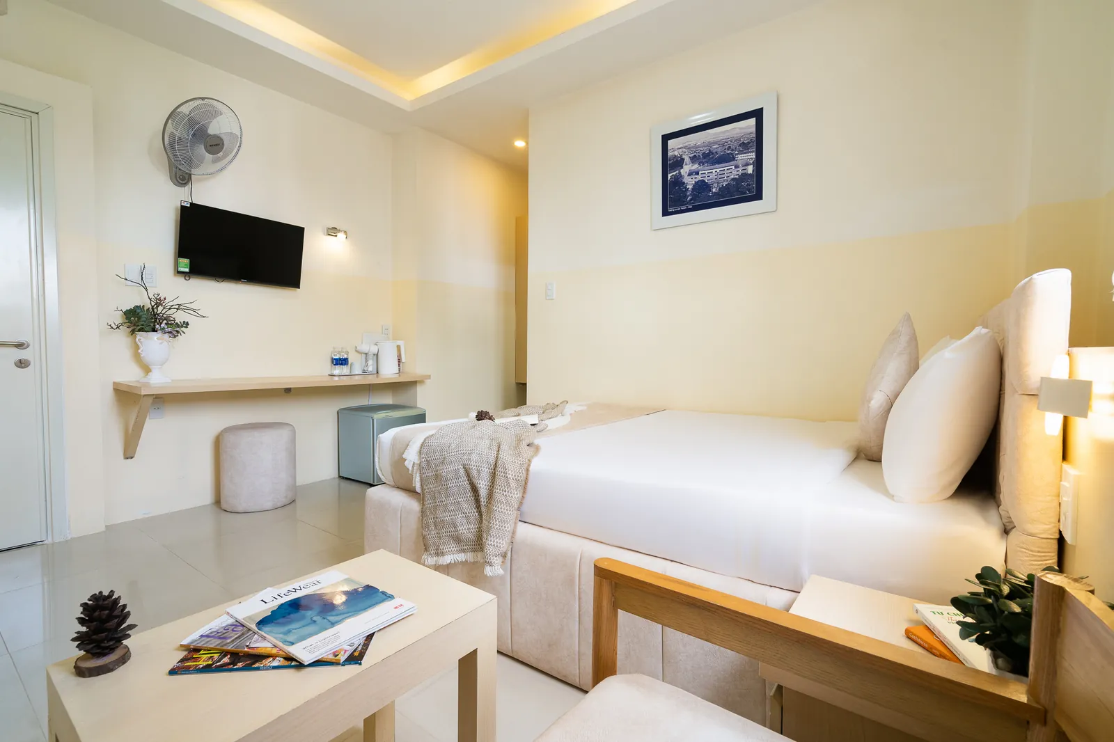 Giường, bàn nhỏ và tranh treo tường trong phòng Deluxe