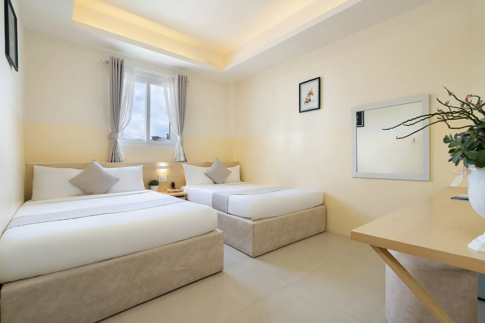 Hai giường 1.4m và bàn gỗ cạnh cửa sổ trong phòng Family